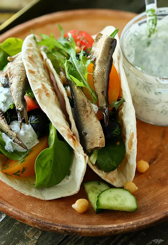 A photo of sardine tacos with queso fresco and fresh vegetables