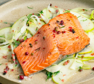 A photo of a fillet of salmon on a bed of vegetables, a meal that can contribute to senior fitness.