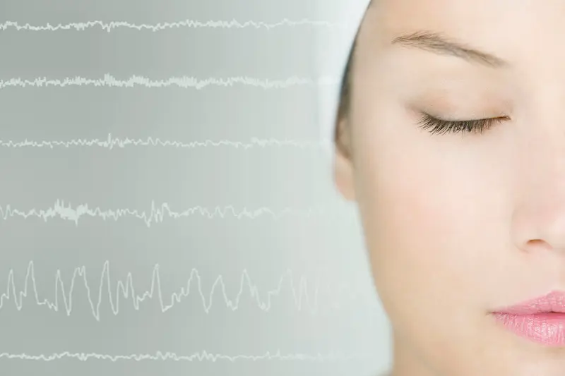 Sleeping woman with brain scan waves in background.