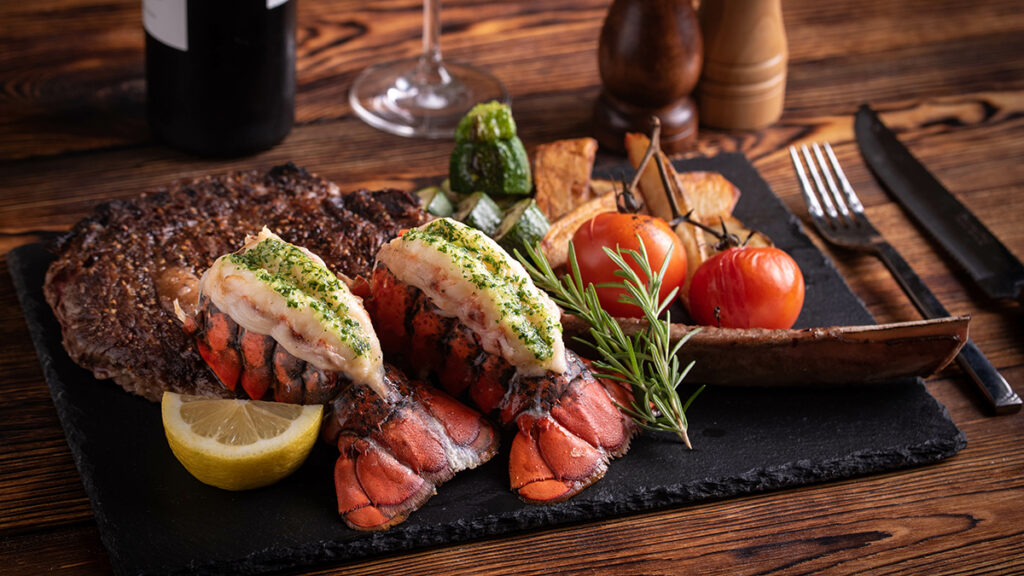 Lobster recipes with a surf and turf meal on a wooden platter.