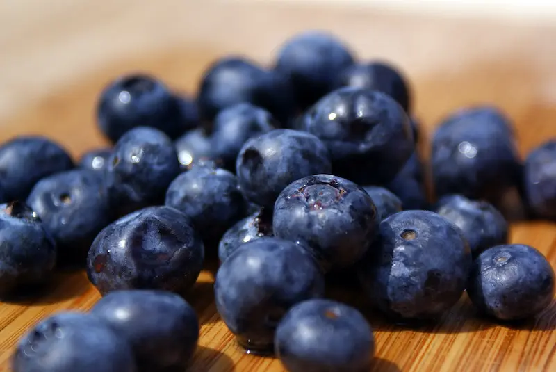 A photo of blueberrry recipes showing a scattering of fresh blueberries on a wooden board.