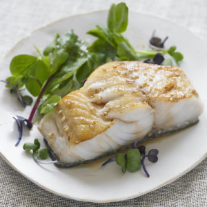 Photo of broiled sablefish on a bed of fresh greens.