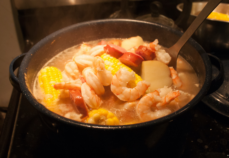 A photo of the low-country boil featuring seafood and corn