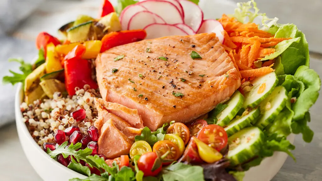 Omega-3 salmon in a bowl with quinoa and other vegetables.