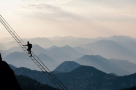 High Altitude Living man on ladder in mountains