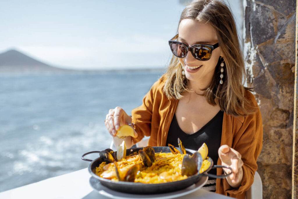 Mediterranean Diet, woman enjoys seafood and pasta dish by the sea. 