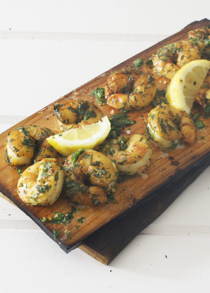 Cooking shrimp, blue shrimp grilled on a cedar plank. 