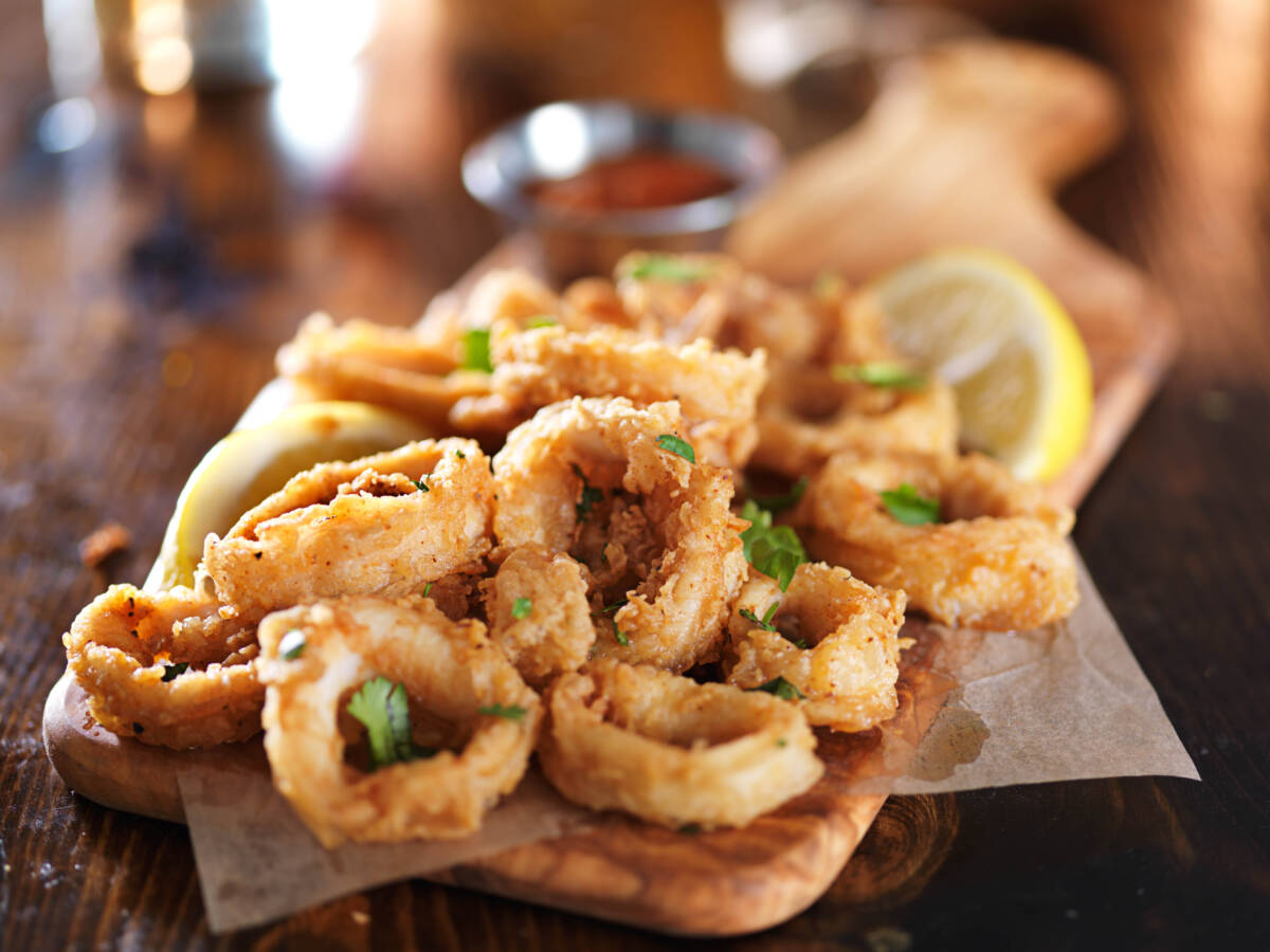 crispy calamari rings on woodne tray with lemon wedge