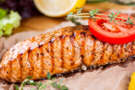Tips for cooking fish with a slice of cooked fish on parchment paper topped with herbs and a slice of tomato.