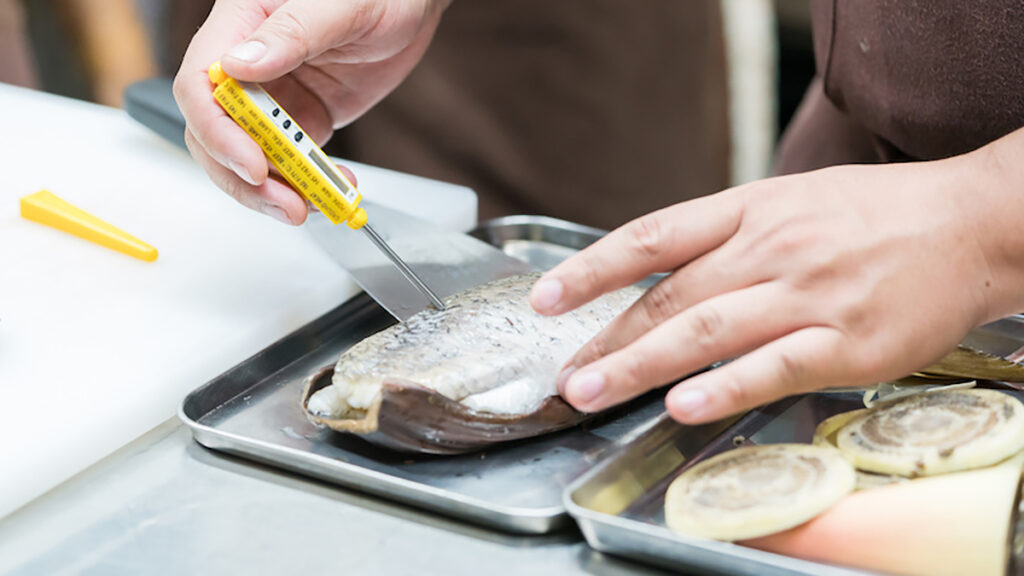 Tips for cooking fish with someone placing a thermometer in a fish.