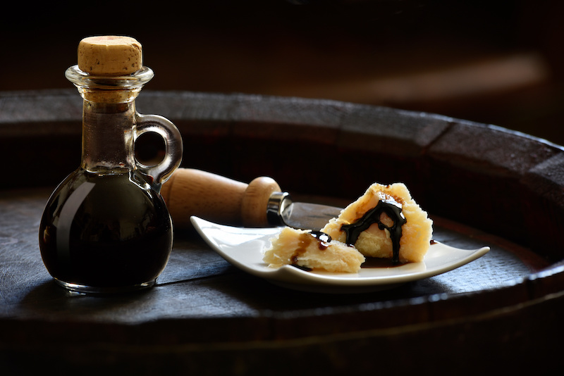 balsamic vinegar recipes showing balsamic drizzled on Parmesan cheese atop a balsamic barrel. 