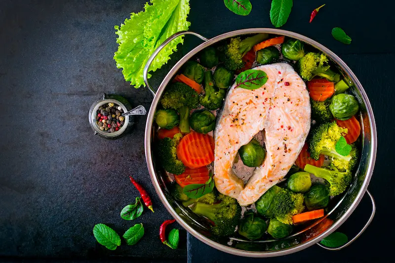 Steamed fish showing salmon steak with vegetables. Top view