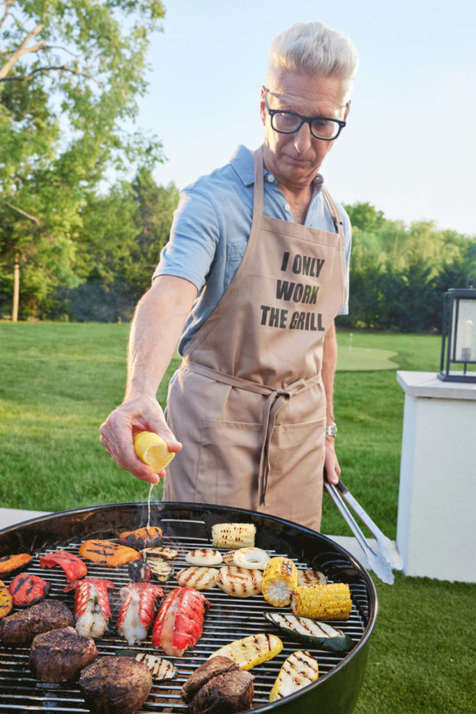 A man showing how to grill various proteins on a charcoal grill.