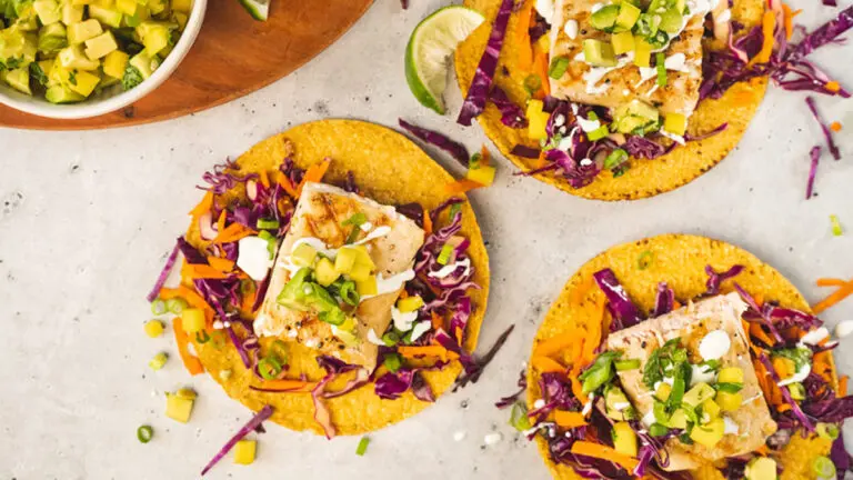 Fish recipes with three grilled fish tostadas with slaw on plates.