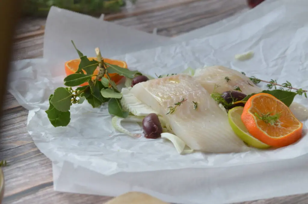 home cooking recipe for halibut in parchment paper with tangerines, olives, fennel and leek