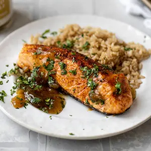 Atlantic salmon with pineapple relish on a plate with rice.