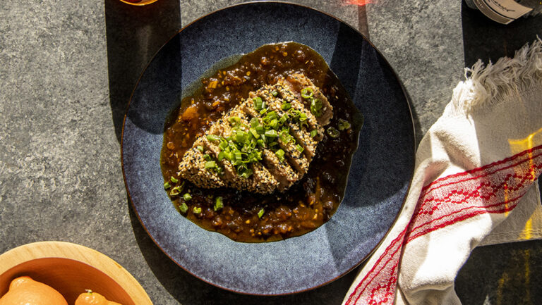 Tuna steak with citrus sauce on a plate.