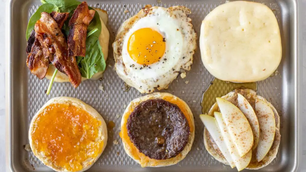 Several breakfast sandwiches on a baking sheet.