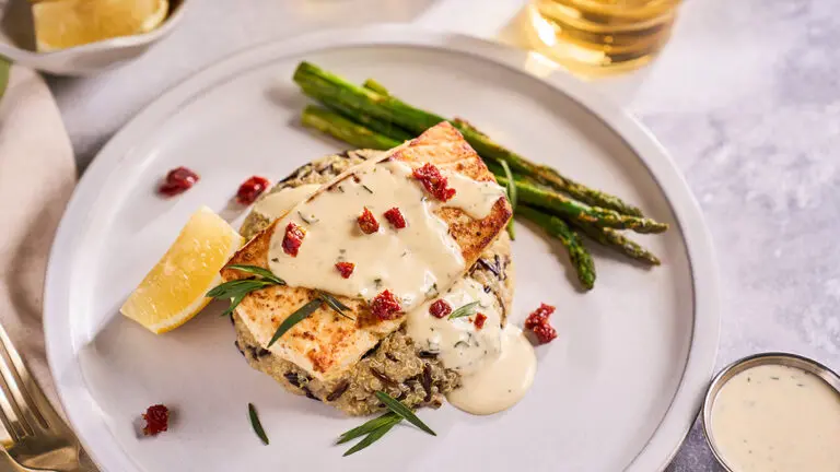 Broiled halibut on a plate with lime aioli and asparagus.