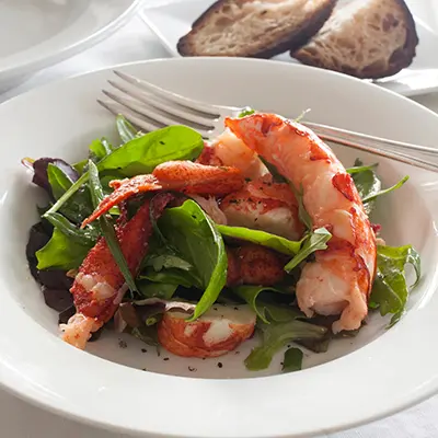 Thanksgiving fish recipes with a plate of cooked lobster on a bed of greens.