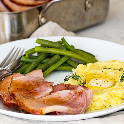Plate of spiral ham, beans, and potatoes for a New Year's dinner idea.