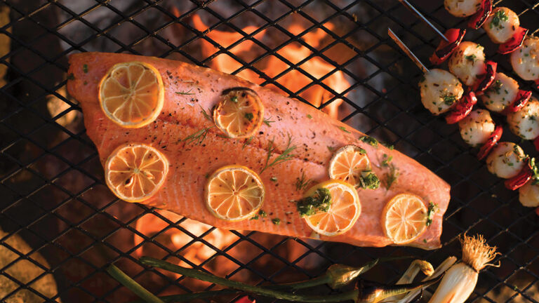 Salmon with lemon slices on a grill.