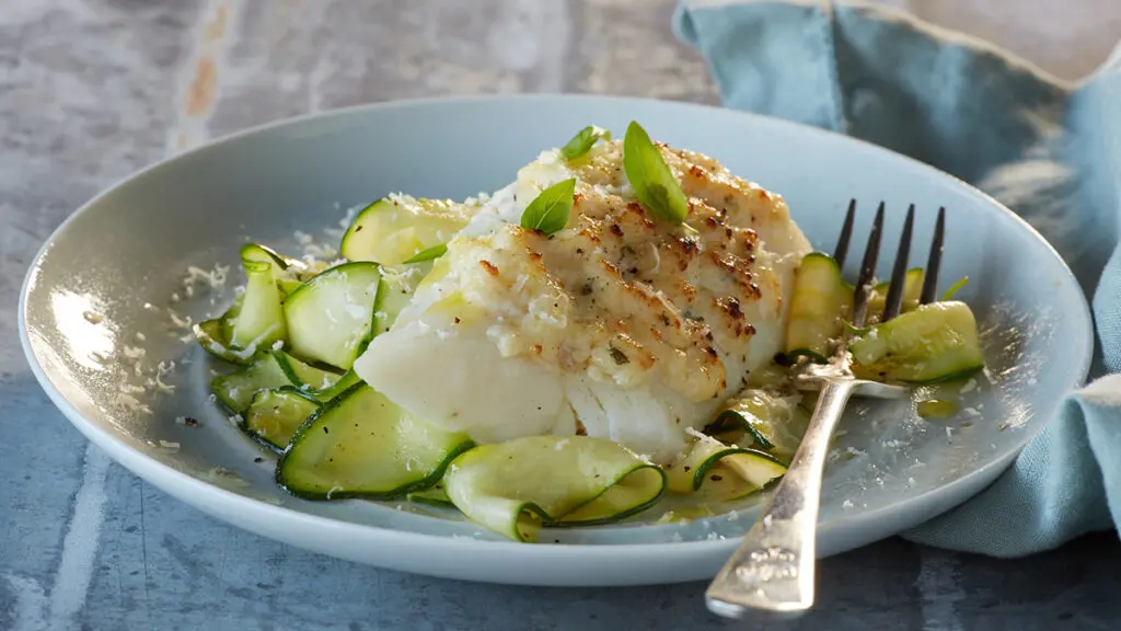 Plate of Alaskan cod with parmesan and zucchini noodles.